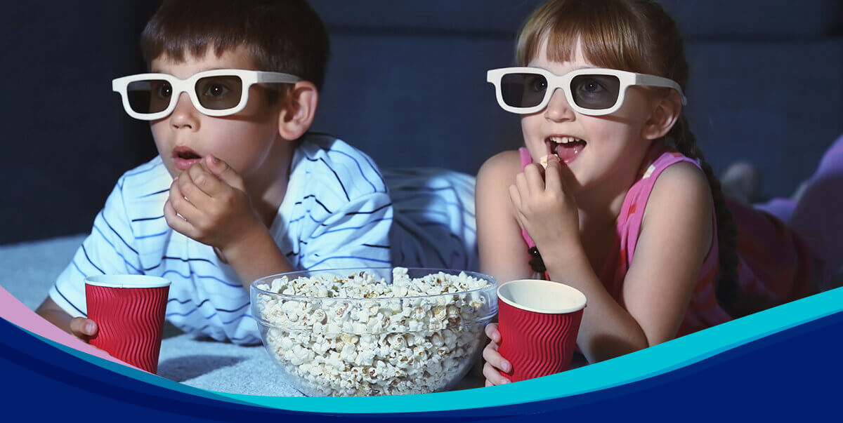 Kids eating popcorn watching a movie