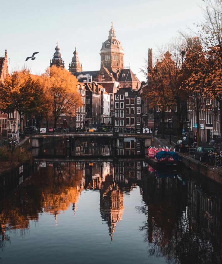 Brown and white concrete building near body of water during daytime in Amsterdam