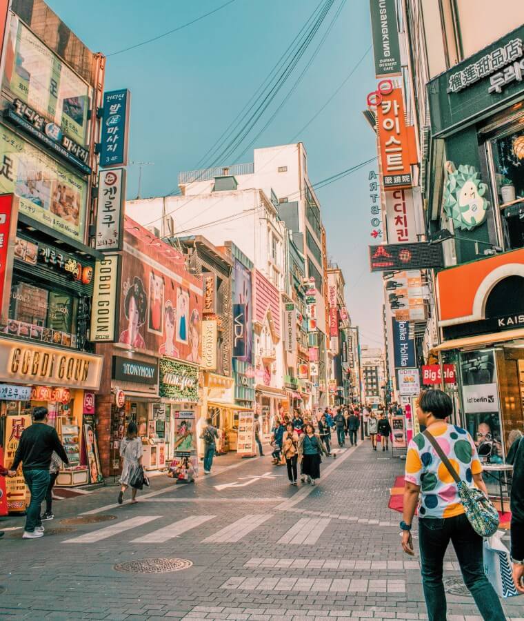 People walking on road surrounded by buildings in the Myeongdong shopping district